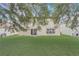 Lush backyard with mature tree coverage and a sliding glass door to the home's interior at 1455 Blue Horizon Dr, Clermont, FL 34714