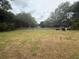 A large, grassy backyard is surrounded by mature trees and a fence, offering privacy and a natural setting at 14598 Se 28Th Ct, Summerfield, FL 34491