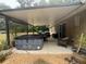 Relaxing covered patio featuring a hot tub, grill, and comfortable outdoor seating area at 14598 Se 28Th Ct, Summerfield, FL 34491