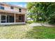 View of the backyard with a screen enclosed porch, partial basketball court, and green grass at 1802 Imperial Palm Dr, Apopka, FL 32712