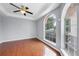 A serene bedroom with hardwood floors, a ceiling fan, and a large arched window at 1802 Imperial Palm Dr, Apopka, FL 32712