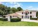 Two-story home featuring a manicured lawn, mature trees, and a circular driveway at 1802 Imperial Palm Dr, Apopka, FL 32712