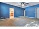 Large bedroom featuring bold blue walls, ceiling fan, neutral carpet, and white doors at 1942 Michael Tiago Cir, Maitland, FL 32751