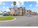 View of the condo community, showing the multi-colored facade and palm trees and ample parking on a sunny day at 2213 Grand Cayman Ct # 1138, Kissimmee, FL 34741
