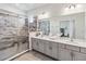 Bathroom features a double sink vanity, large mirror, and glass-enclosed shower with gray tile at 2574 Shanti Dr, Kissimmee, FL 34746