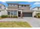 Modern home with two-car garage, gray driveway, landscaping, and a two-tone gray and white facade at 2574 Shanti Dr, Kissimmee, FL 34746