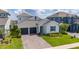 Charming one-story home featuring a brick-paved driveway, two-car garage, and well-manicured lawn with bushes at 2591 Seagirt Way, Clermont, FL 34711