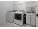 Bright laundry room features modern washer and dryer, sink with white cabinets, and stylish tile backsplash at 2591 Seagirt Way, Clermont, FL 34711