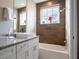 Bright bathroom featuring a modern vanity with granite countertop, a tub, and a wood-look tile accent wall at 2660 Sunrise Shores Dr, Kissimmee, FL 34747