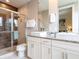Modern bathroom showcasing double sinks with a glass door shower, neutral tiles, and granite countertop at 2660 Sunrise Shores Dr, Kissimmee, FL 34747