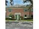 Charming brick townhouse featuring a well-manicured lawn, lush greenery, and coordinated green doors and shutters at 316 Georgetown Dr, Casselberry, FL 32707