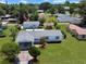 An aerial view showcases a single-story home with a well-manicured lawn, carport, and vibrant blue shutters at 413 5Th S St, Dundee, FL 33838