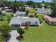 Aerial view of single-story home featuring a well-manicured lawn, garage, and mature trees at 413 5Th S St, Dundee, FL 33838