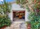 View of an open one-car garage filled with equipment, as seen from the driveway framed by trees at 413 5Th S St, Dundee, FL 33838