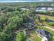 Overhead view of well-manicured neighborhood, home with circle drive, mature trees, and nearby pond at 502 Canopy Ln, Lady Lake, FL 32159