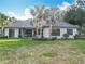 Beautiful home featuring lush green lawn, complemented by tropical palm trees and shrubbery at 502 Canopy Ln, Lady Lake, FL 32159