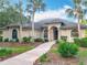 Stunning home exterior featuring a well-manicured lawn, palm trees, and a curved walkway to the front door at 502 Canopy Ln, Lady Lake, FL 32159