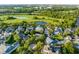 An aerial view showcasing a neighborhood's homes surrounded by lush greenery, a golf course, and a serene lake at 506 Golfpark Dr, Celebration, FL 34747