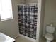 Bathroom featuring a toilet and tiled shower with a patterned curtain at 5267 Images Cir # 102, Kissimmee, FL 34746