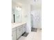 Bright bathroom featuring double vanity sinks with modern fixtures, a glass-enclosed shower, and clean white tile at 542 Pine Tree Bridge Trl, St Cloud, FL 34772