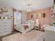 Charming bedroom with blush accent wall, decorative chandelier and warm natural light at 5457 Carrara Ct, St Cloud, FL 34771
