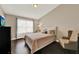 Neutral bedroom featuring a window, wood floors, and an accent chair with a dark dresser at 6201 Goethe St # 103, Orlando, FL 32835