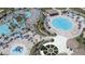 Aerial view of a community pool area with water slides, cabanas, and ample seating surrounded by tropical trees at 725 Ocean Course Ave, Davenport, FL 33896