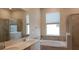 Bathroom features a dual sink vanity, a soaking tub, a separate shower, and a window at 725 Ocean Course Ave, Davenport, FL 33896