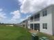 Back exterior view of a row of townhomes, each with a screened-in patio or balcony, set against a grassy area at 725 Ocean Course Ave, Davenport, FL 33896