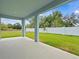 View from a covered patio showing a grassy lawn enclosed by a white fence and mature trees at 8018 Colby Cir, Orlando, FL 32817