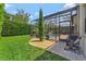 Grassy backyard with stone edged garden beds, leading to a screened-in pool area at 8439 Prestbury Dr, Orlando, FL 32832