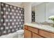 Full bath with a shower featuring a patterned curtain, granite counters, and warm cabinetry at 8439 Prestbury Dr, Orlando, FL 32832