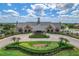 Exterior aerial view of a community clubhouse with lush landscaping, a paved driveway, and a clock tower at 8439 Prestbury Dr, Orlando, FL 32832