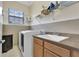 Bright laundry room with a large window, washer, dryer, utility sink, and plenty of storage space at 8439 Prestbury Dr, Orlando, FL 32832