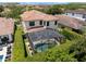 Aerial view of backyard pool with screen enclosure, lush landscaping, and neutral colored two-story home with a terracotta roof at 8439 Prestbury Dr, Orlando, FL 32832