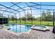 Inviting pool and spa in a screened enclosure, surrounded by brick pavers and greenery at 9104 Stromboli Ct, Kissimmee, FL 34747