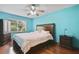 Relaxing bedroom with blue walls, hardwood floors, a queen bed, and natural light from a large window at 1016 Seminole Creek Dr, Oviedo, FL 32765
