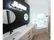 Modern bathroom with dual sinks, a large mirror, and a soaking tub near a window at 10255 Cody Ln, Orlando, FL 32825