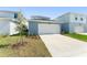Garage of home features a white door and grey walls, with landscaping around the front of the driveway at 10959 Vesper Aly, Orlando, FL 32829