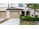 Charming two-story townhome featuring a beige garage door, neutral stucco, and manicured green shrubbery at 1109 Pavia Dr, Apopka, FL 32703