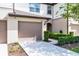 Charming two-story townhome featuring a beige garage door, neutral stucco, and manicured green shrubbery at 1109 Pavia Dr, Apopka, FL 32703