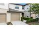 Charming two-story townhome featuring a beige garage door, neutral stucco, and manicured green shrubbery at 1109 Pavia Dr, Apopka, FL 32703