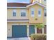 Inviting two-story home with a teal garage door, updated front door, and tropical shrubbery at 12212 Wild Iris Way # 106, Orlando, FL 32837