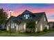 Charming two-story home with a manicured lawn, stone accents, and a welcoming front porch at twilight at 13347 Gabor Ave, Orlando, FL 32827
