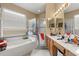 Bright bathroom featuring double sinks, vanity, tub, and a glass enclosed shower at 13609 Sky Blue Ct, Orlando, FL 32828