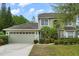 Two-story home boasts an attached garage, lush landscaping, and mature trees in a well-maintained front yard at 13609 Sky Blue Ct, Orlando, FL 32828