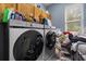 Bright laundry room with front-loading Samsung washer and dryer and wooden cabinets at 13609 Sky Blue Ct, Orlando, FL 32828