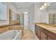 Bright bathroom featuring a soaking tub, glass shower, and double sink vanity with granite countertop and tiled floor at 13913 Hahn Ln, Orlando, FL 32827