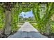 Picturesque community walkway and manicured landscaping are viewed from a pergola covered in climbing vines at 13913 Hahn Ln, Orlando, FL 32827