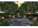 Night view of picturesque community walkway features lush landscaping, mature trees, benches, and welcoming ambiance with lighting at 13913 Hahn Ln, Orlando, FL 32827